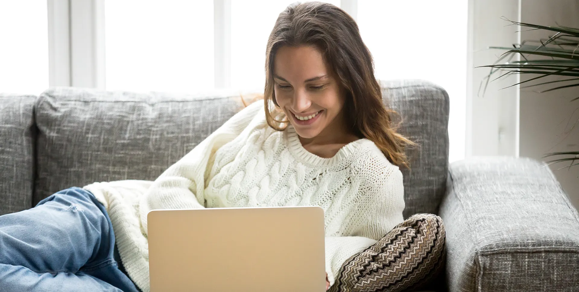 Ženska na kavču z računalnikom nakupuje v spletni trgovini